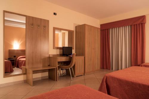 um quarto de hotel com um quarto com 2 camas e uma secretária em Manhattan Village Hotel em Sulmona