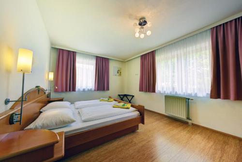 a bedroom with a large bed with red curtains at Feriendorf Rosental by S4Y - Selbstversorger Appartements in Feistritz im Rosental