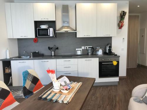 une cuisine avec des armoires blanches et une table en bois dans l'établissement Chouette Massena, à Nice