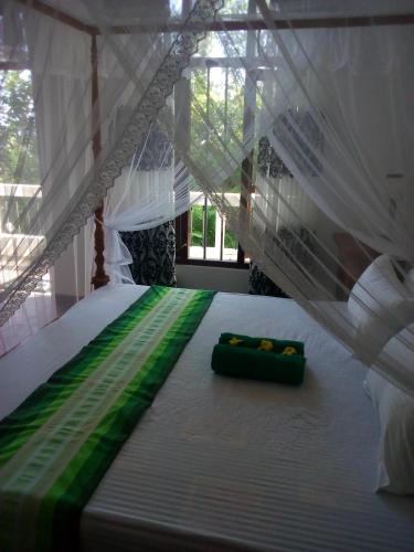 a white bed with a green and white canopy at Daasa Guest Mirissa in Mirissa