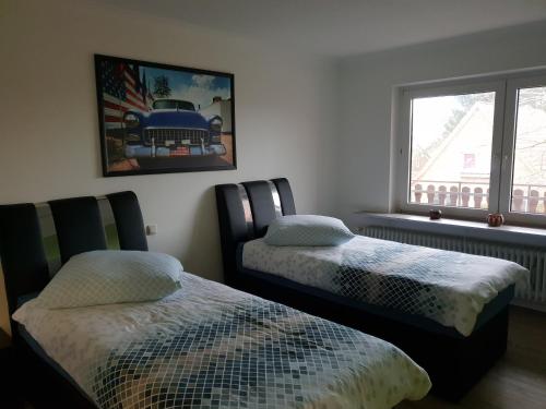 2 Betten in einem Zimmer mit einem Bild eines Autos an der Wand in der Unterkunft Sunnesching in Sankt Michaelisdonn