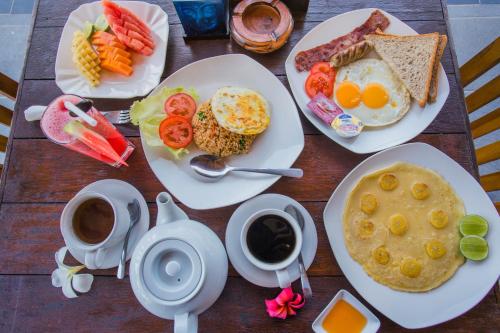 a table with plates of breakfast foods and cups of coffee at Sunset Coin Lembongan in Nusa Lembongan