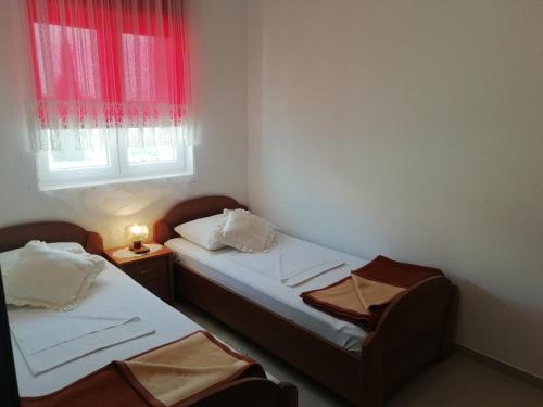 two beds in a small room with a window at Apartments Vidović in Vodice