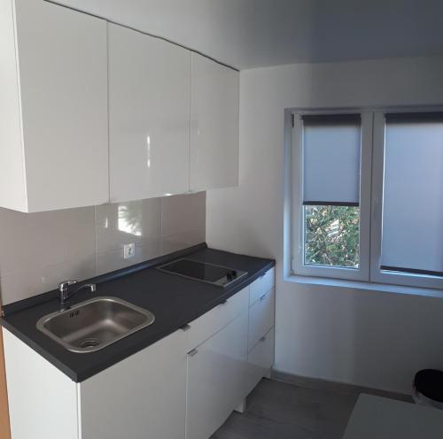 a white kitchen with a sink and a window at Apartment Aquamarine in Vir