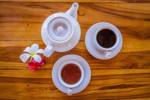 two cups of coffee and a tea pot on a wooden table at D'Coin Lembongan in Nusa Lembongan