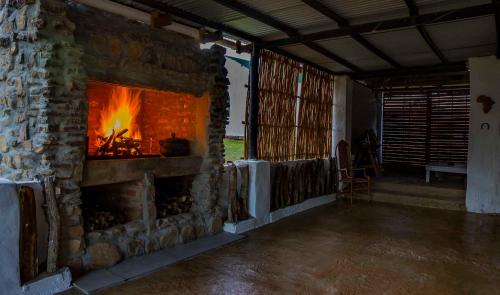 a stone fireplace in a room with a fire in it at Kromrivier Farm Stays & B&B Near Addo Elephant Park in Paterson