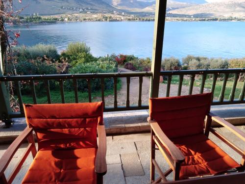 two chairs sitting on a porch overlooking the water at Aphrodite's Coast Retreat House! in Galaxidhion