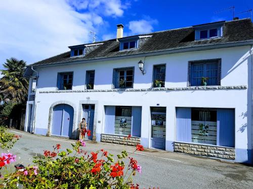 a white house with blue windows and flowers at Chambres d'hôtes Chez Valérie in Arette