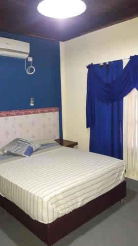 1 dormitorio con 1 cama con pared azul en Flia Ocampo en Puerto Iguazú
