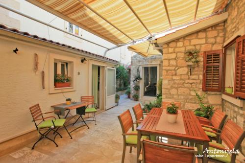 un patio al aire libre con mesas, sillas y toldo en Apartment & Rooms Antonijela, en Bol