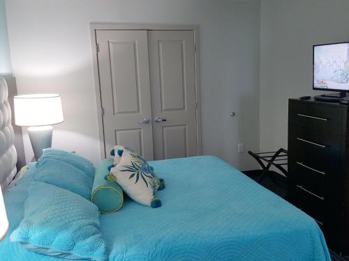 a bedroom with a blue bed with pillows and a television at 1906 OO in Myrtle Beach