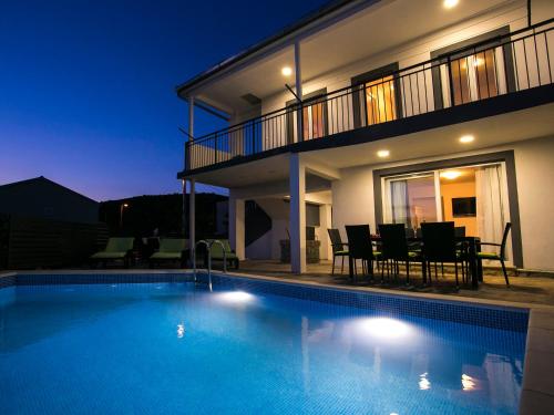 - une piscine en face d'une maison la nuit dans l'établissement Villa Croatia Sea View with heated pool, à Vinišće