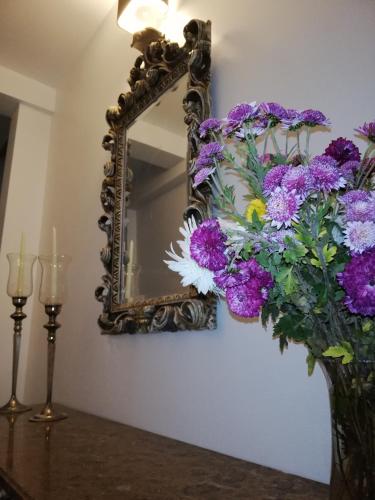a mirror on a wall with purple flowers in a vase at Memórias Charme Residences in Covilhã