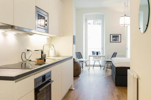 uma cozinha branca com um lavatório e uma sala de estar em The BL42 - Vienna Concept Apartments em Viena