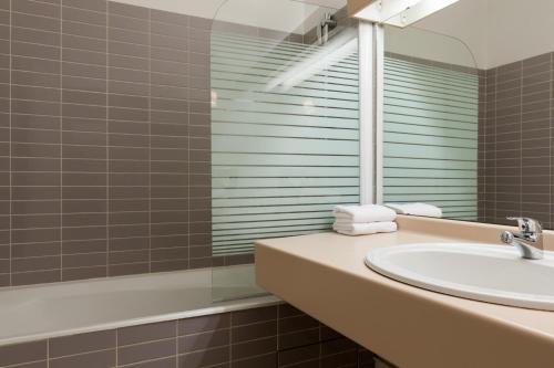 ein Bad mit einem Waschbecken und einem Spiegel in der Unterkunft La Berteliere, The Originals Relais (Qualys-Hotel) in Saint-Martin-du-Vivier
