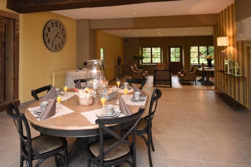 una sala da pranzo con tavolo, sedie e orologio di La Corrérie a Les Grandes-Armoises