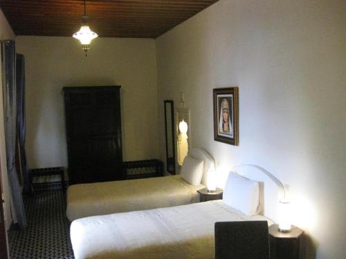 a hotel room with two beds and two lamps at Riad Sabah in Fès