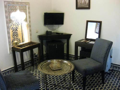 a living room with a table and a chair and a desk at Riad Sabah in Fès