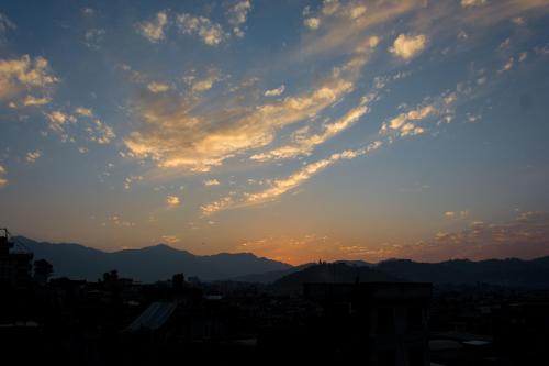 a sunset over a city with mountains in the background at Wander Thirst in Kathmandu