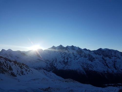 a sun setting over a snow covered mountain range at Sunshine in Saas-Grund