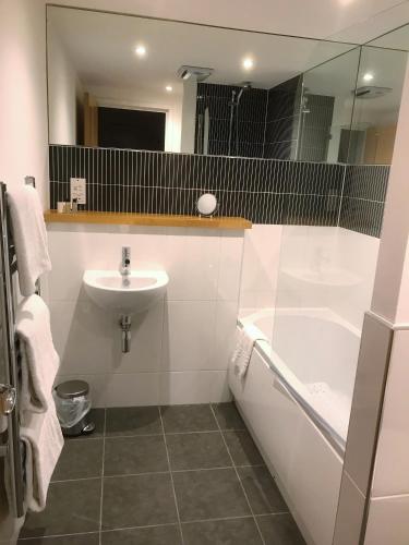 a bathroom with a sink and a tub and a toilet at Ice House Apartments in Swansea