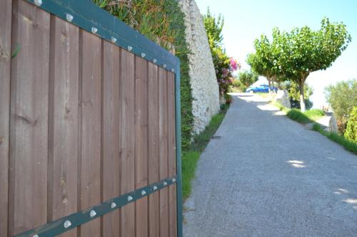 a wooden fence next to a road with trees at Althea Studios Lefkada in Agios Nikitas