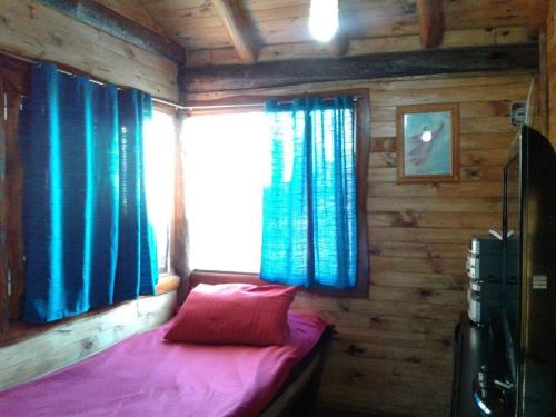 1 dormitorio pequeño con 1 cama en una cabaña de madera en cabañas Khuska en Bialet Massé