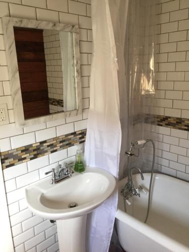 een badkamer met een wastafel en een bad met een spiegel bij Crescent City Cottage in New Orleans