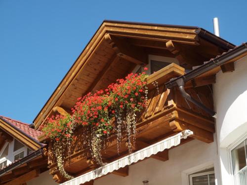 a balcony with red flowers on a building at Apart Rustica in Kaunertal
