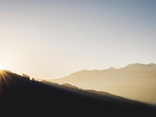 a hillside with the sun shining on the horizon at Hanserhof in Zell am Ziller