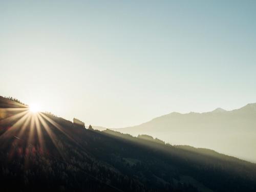 a sun is setting on a hill with trees at Hanserhof in Zell am Ziller
