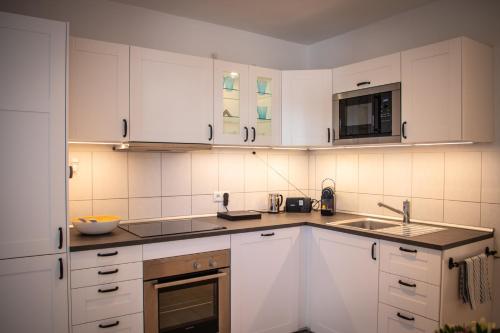 eine Küche mit weißen Schränken, einer Spüle und einer Mikrowelle in der Unterkunft Liebesvolles Studio in Eppstein in Eppstein