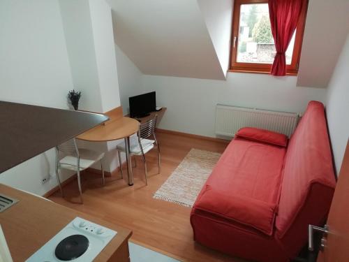 a living room with a red couch and a table at Privát Kompišovci in Liptovský Ján