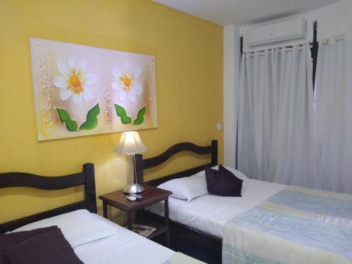 a bedroom with two beds and a painting of flowers at Hotel Pousada Laje de Itauna in Saquarema