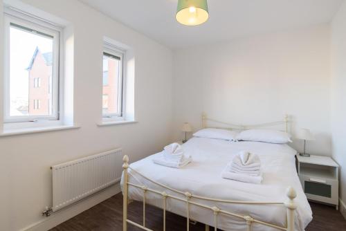 um quarto com uma cama com lençóis brancos e 2 janelas em Bramante Heights em Newport