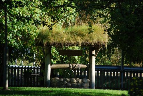 a grass roofed gazebo with rocks and a fence at Klækken Hotel in Hønefoss