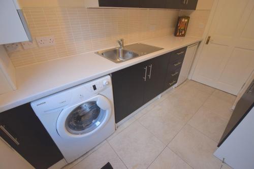una cocina con lavadora y fregadero en Ashburn Cottage, en Lochgoilhead