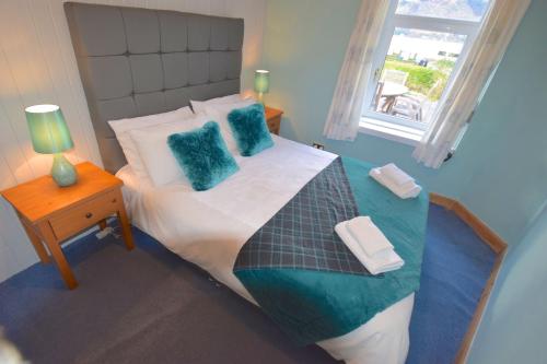 Un dormitorio con una cama con almohadas azules y una ventana. en Ashburn Cottage, en Lochgoilhead