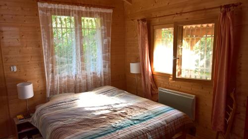 Gîtes Le Panorama في Collonges-sous-Salève: غرفة نوم مع سرير ونوافذ في كابينة خشب