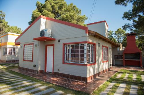 una pequeña casa blanca con techo rojo en Cabañas Las Dunas en Monte Hermoso