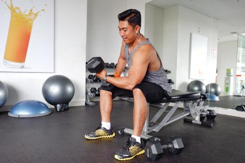a man sitting on a bench in a gym at HARRIS Hotel and Conventions Denpasar Bali in Denpasar