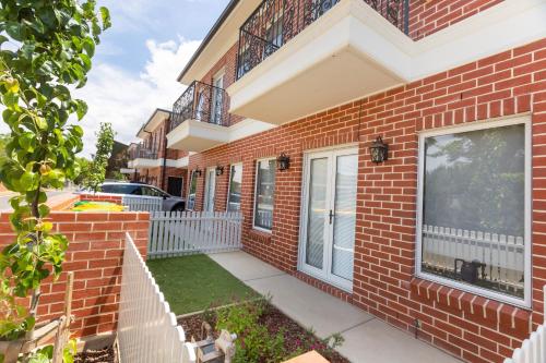 a brick house with a white fence next to it at Glen’s Inner City Escape - CBD Central in Wagga Wagga