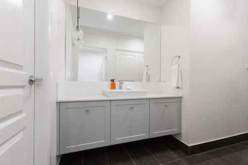 ein weißes Badezimmer mit einem Waschbecken und einem Spiegel in der Unterkunft 4 Bedroom Inner City Townhouse - SLEEPS 9 !! in Wagga Wagga