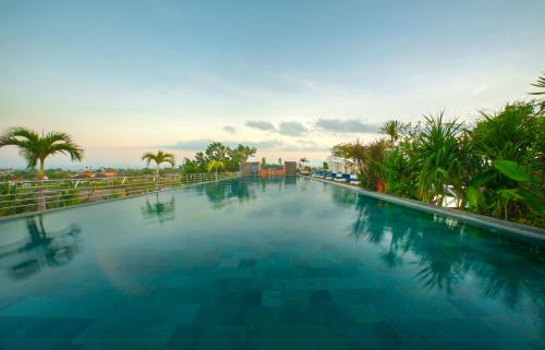 a large swimming pool with blue water and palm trees at de Vins Sky Hotel Seminyak in Seminyak