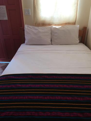 a bed with white sheets and pillows in a room at Ambergris Sunset Hotel in San Pedro