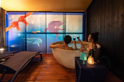 un uomo e una donna in una vasca da bagno con un acquario di XYZ Private Spa and Seaside Resort a Shirahama