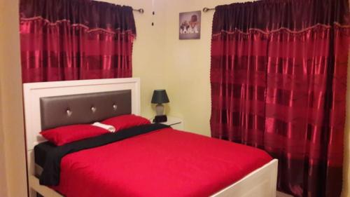 a bedroom with a red bed with red curtains at Wilks Villa in Knowles