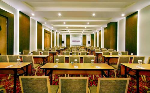 a conference room with tables and chairs and a screen at favehotel Braga in Bandung