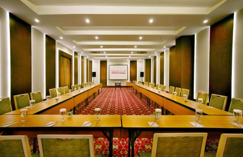 a conference room with long tables and chairs and a presentation at favehotel Braga in Bandung