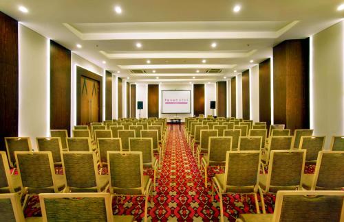 a room with rows of chairs and a projection screen at favehotel Braga in Bandung